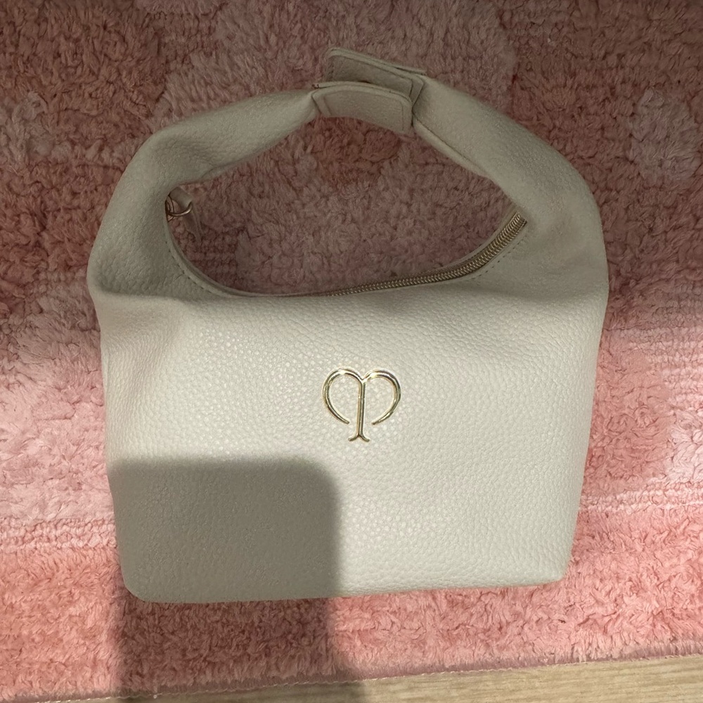 Cle de peau Cream/ivory small makeup bag that looks like a cute little handbag.